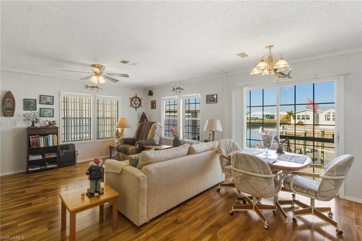 Living room featuring a water view, a ceiling fan, wood finished floors, a textured ceiling, and a chandelier