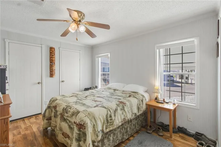 Bedroom featuring ornamental molding, wood finished floors, a ceiling fan, and a textured ceiling