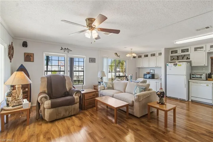 Living area with light wood-type flooring, a textured ceiling, ceiling fan, and a chandelier