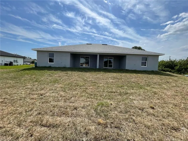 Back of house with a lawn and stucco siding