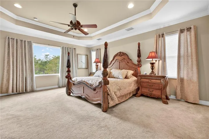 Bedroom featuring a tray ceiling, carpet, crown molding, and a ceiling fan
