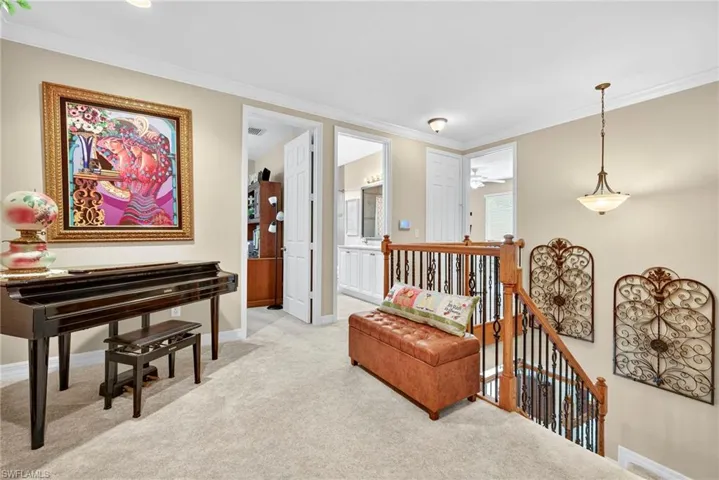 Sitting room with an upstairs landing, ornamental molding, and light colored carpet