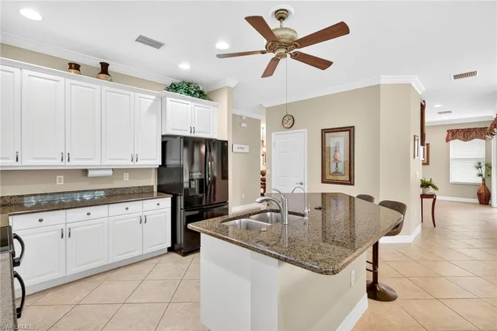 Kitchen featuring dark stone counters, white cabinetry, black appliances, a breakfast bar, and recessed lighting