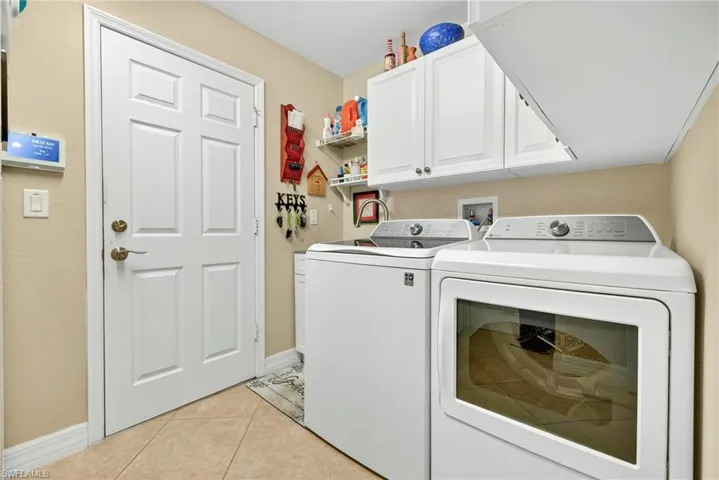 Washroom with light tile patterned floors, cabinet space, and washing machine and clothes dryer