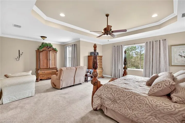 Bedroom featuring a tray ceiling, crown molding, light colored carpet, ceiling fan, and recessed lighting