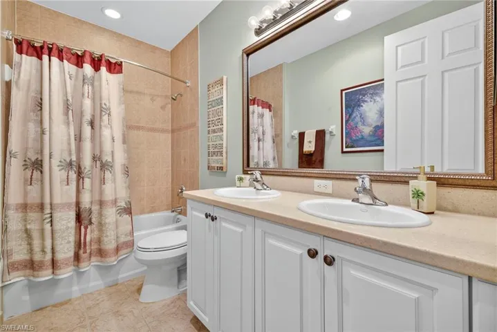 Bathroom with shower / bath combination with curtain, double vanity, light tile patterned flooring, and recessed lighting