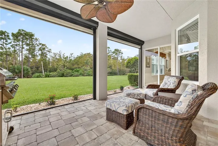 Sunroom with a ceiling fan, a patio area, and view of wooded area