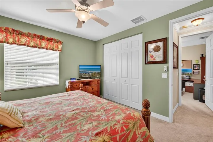 Bedroom with light colored carpet, a closet, and a ceiling fan