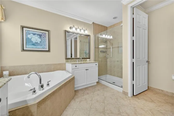 Full bathroom with ornamental molding, vanity, a garden tub, a shower stall, and light tile patterned flooring