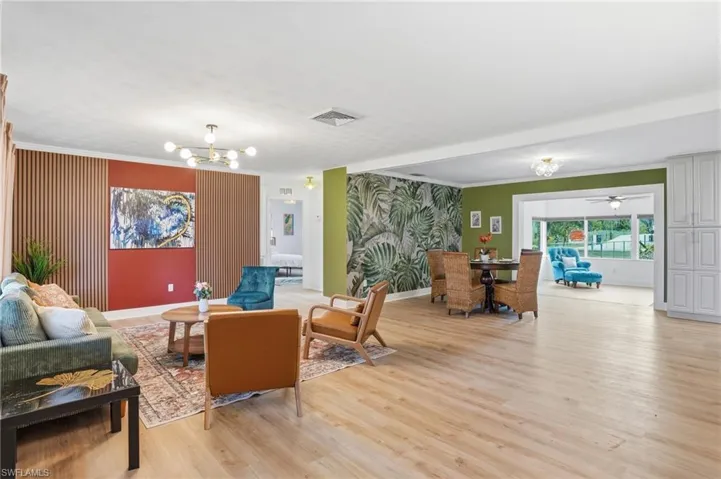 Open-concept living area featuring wood-finish flooring, a contemporary chandelier, and recessed lighting