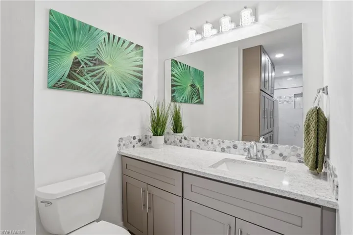 Bathroom featuring a single vanity with a white rectangular sink, light-toned countertop, and a decorative tile backsplash