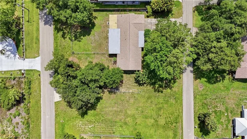 Aerial perspective highlighting a residential property with a brown shingle roof and a detached carport