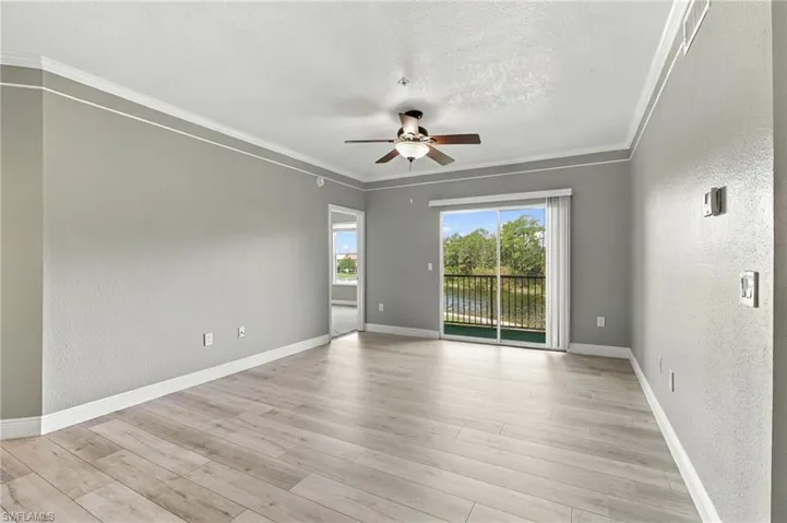 Light wood-finish flooring, crown molding, and a ceiling fan with light fixture