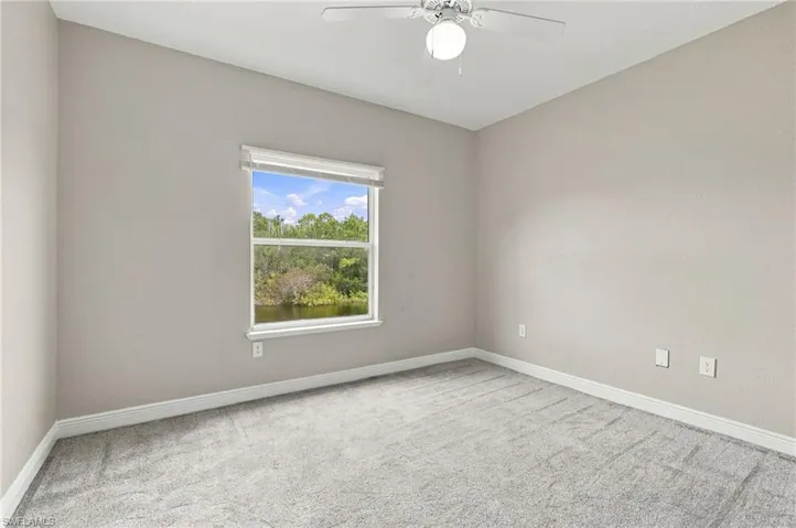 Room featuring light gray walls, gray carpeting, a single window with white blinds, and a ceiling fan with integrated lighting