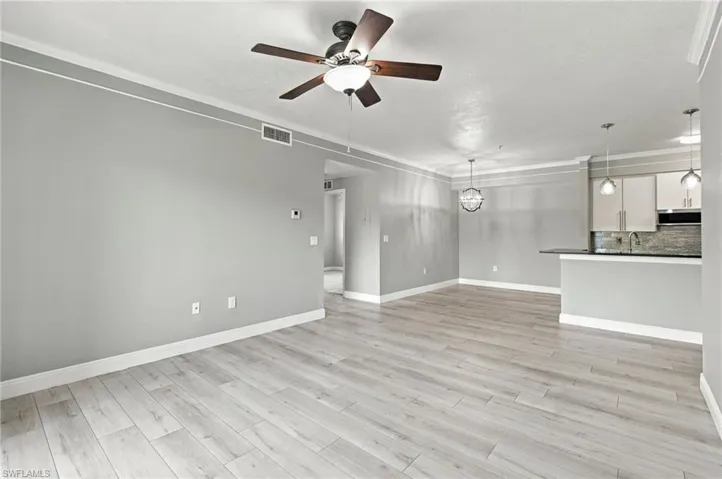 Light wood-finish flooring, crown molding, and a ceiling fan