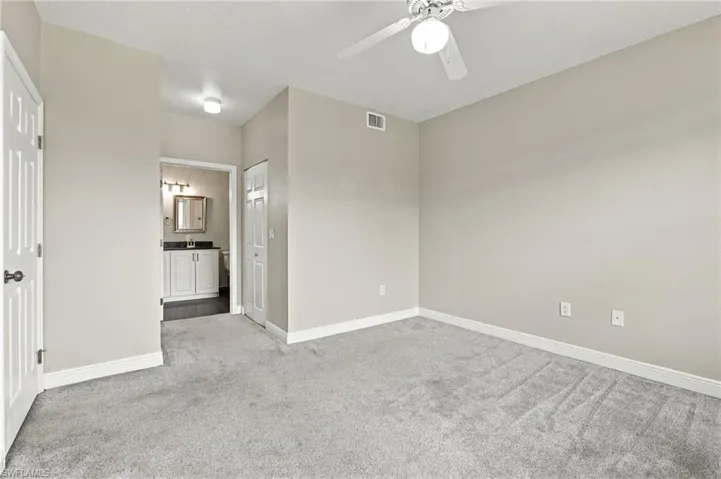Carpeted room with a ceiling fan, a white paneled door, and a white bi-fold door