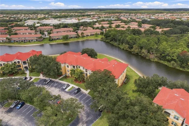 Residential complex featuring terracotta tile roofs, a large body of water, and surrounding green spaces