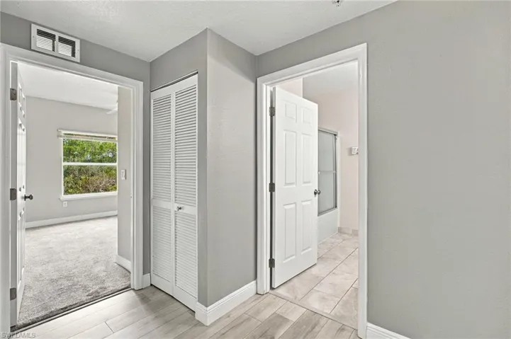Wood-finish flooring, paneled interior doors, louvered bi-fold closet, and neutral wall tones