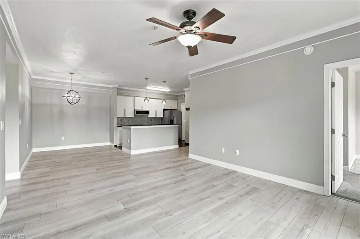 Light wood-finish flooring throughout, crown molding, modern ceiling fan, contemporary orb chandelier, and recessed lighting