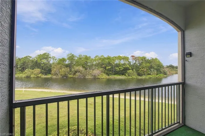 Balcony with metal railing overlooking a body of water and treeline