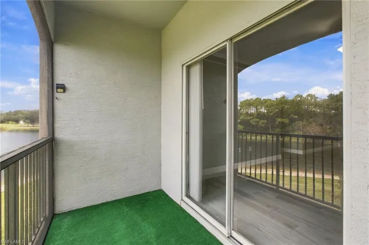 Screened balcony with textured exterior walls, sliding glass door, and a metal railing