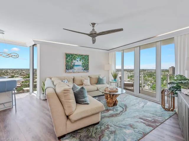 Living area featuring expansive windows, healthy amount of natural light, wood finished floors, and ceiling fan
