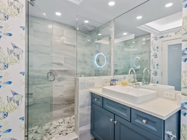 Bathroom with a shower stall, vanity, tile walls, and recessed lighting