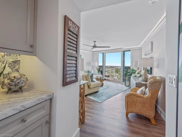Living room with wood finished floors, ornamental molding, a ceiling fan, and expansive windows