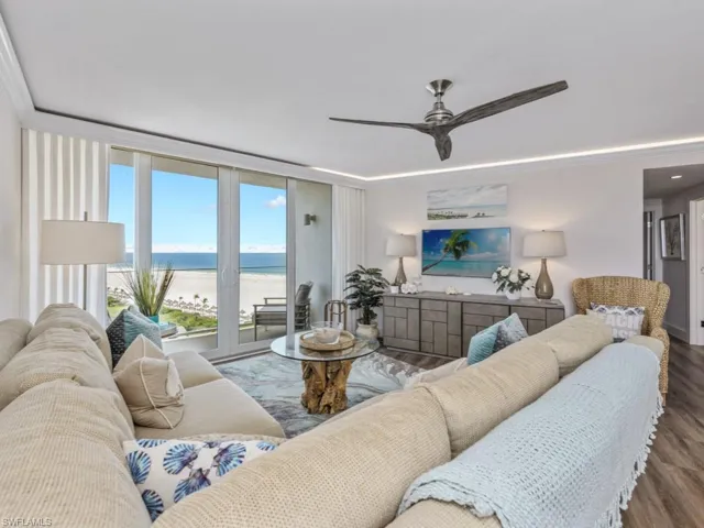 Living area featuring ceiling fan, wood finished floors, expansive windows, and crown molding