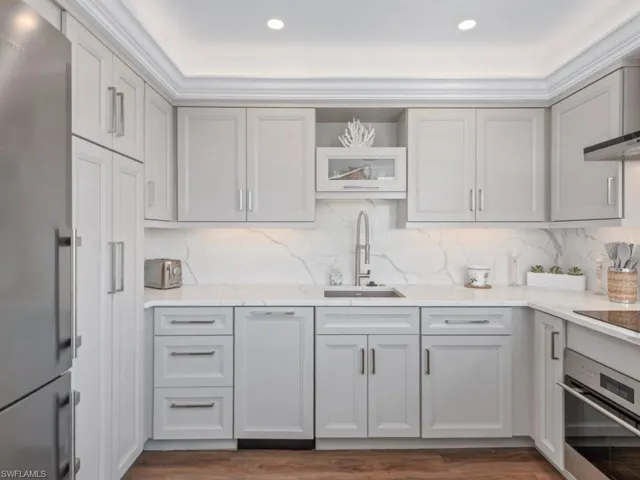 Kitchen with stainless steel appliances, dark wood-type flooring, tasteful backsplash, and light stone countertops