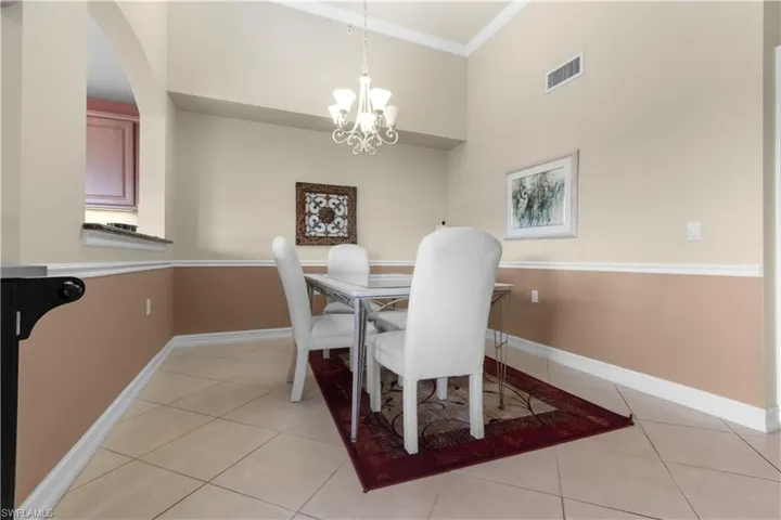 Dining area featuring vaulted ceilings, a decorative chandelier, wainscoting, and tile flooring