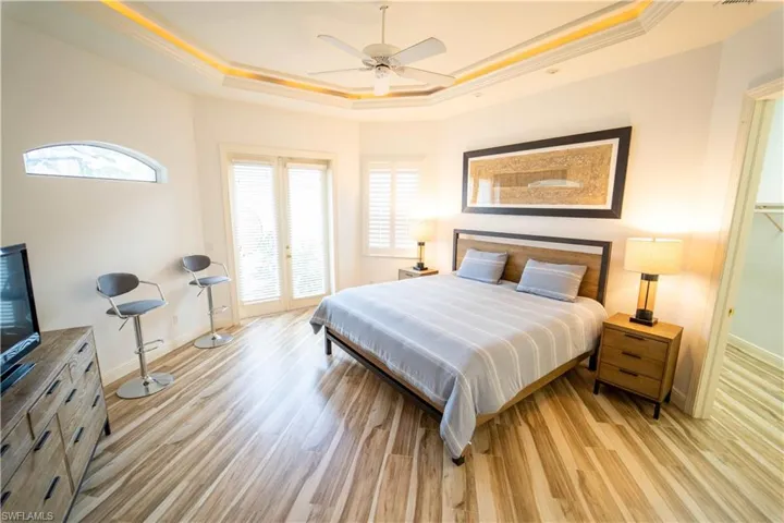 Bedroom with a raised ceiling, ornamental molding, ceiling fan, and light hardwood / wood-style flooring