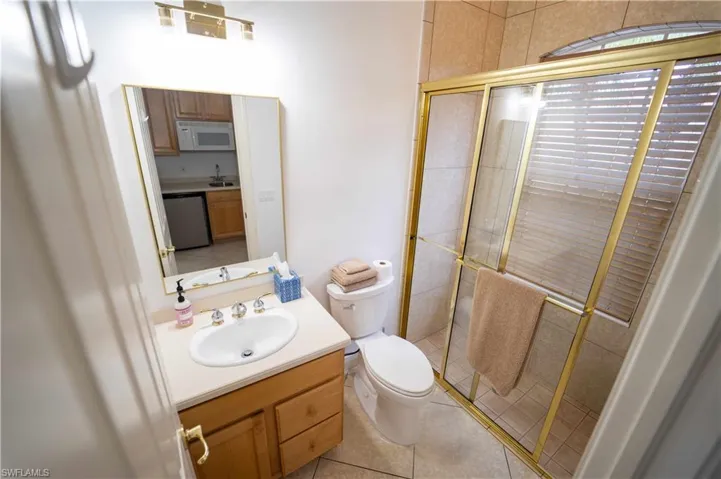 Bathroom featuring tile patterned floors, a shower with door, vanity, and toilet