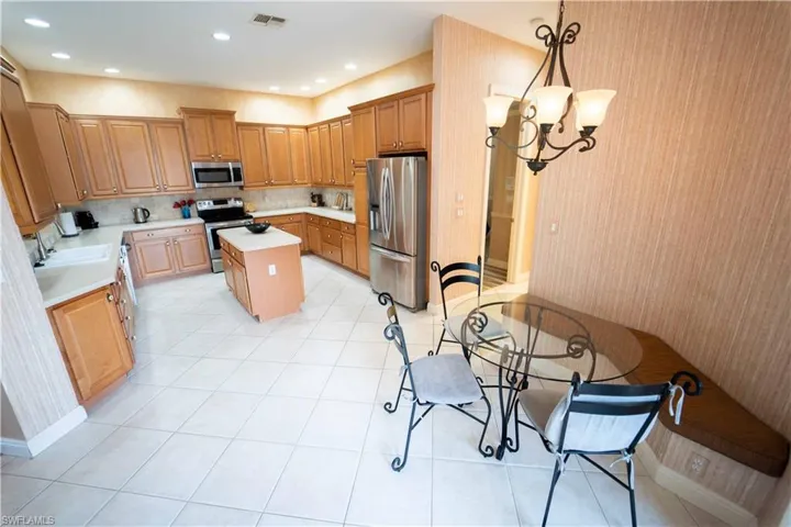 Kitchen with pendant lighting, a chandelier, tasteful backsplash, a kitchen island, and appliances with stainless steel finishes