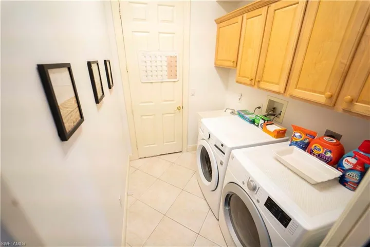 Washroom featuring light tile patterned floors, independent washer and dryer, and cabinets