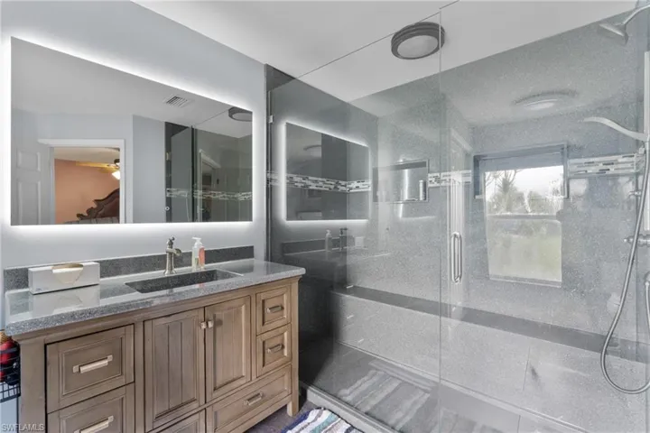 Bathroom with vanity, a stall shower, and a ceiling fan