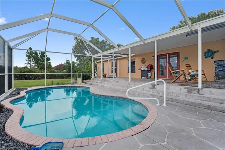 Swimming pool featuring glass enclosure, a patio, a sunroom, area for grilling, and french doors
