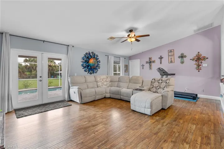 Living room with hardwood / wood-style floors, plenty of natural light, french doors, and ceiling fan