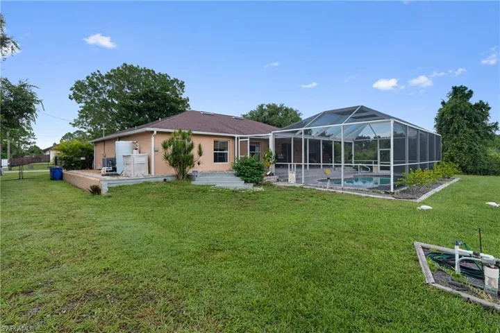 Rear view of property featuring a patio area, a sunroom, stucco siding, a lanai, and a yard