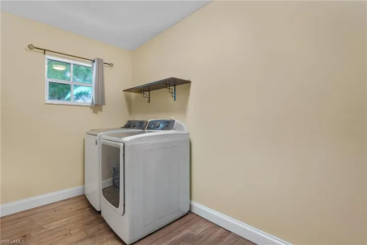 Laundry area with separate washer and dryer and light wood-type flooring