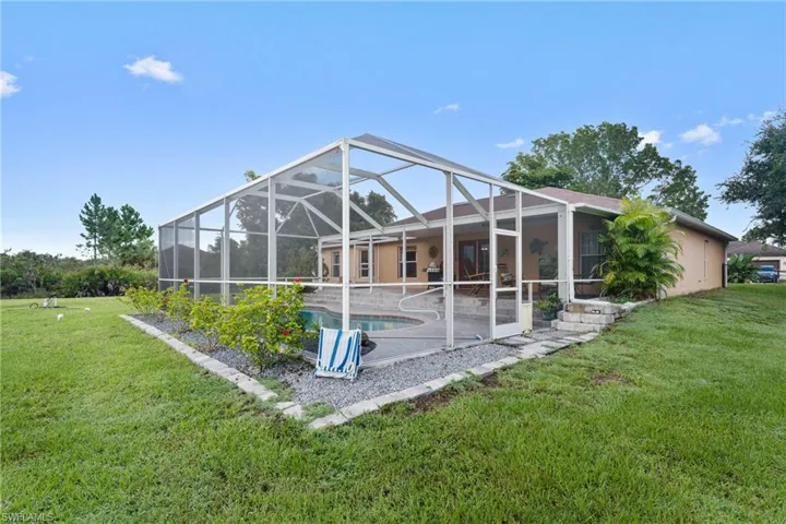 Rear view of house with a yard, an outdoor pool, a sunroom, and a lanai