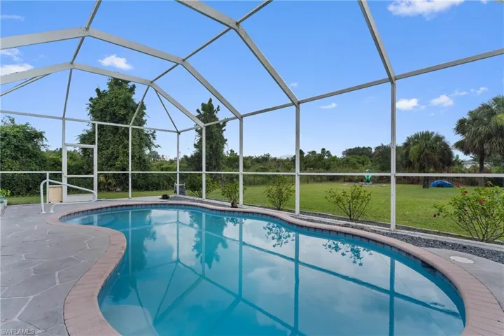 Outdoor pool with a sunroom, a yard, and glass enclosure