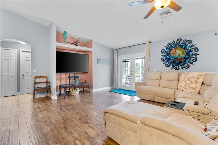 Living area featuring lofted ceiling, hardwood / wood-style flooring, ceiling fan, french doors, and arched walkways