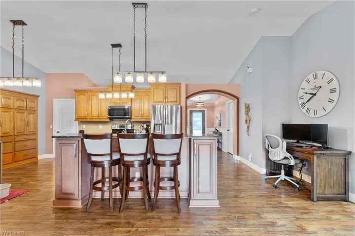 Kitchen featuring a kitchen bar, arched walkways, a kitchen island with sink, stainless steel appliances, and light wood-style flooring