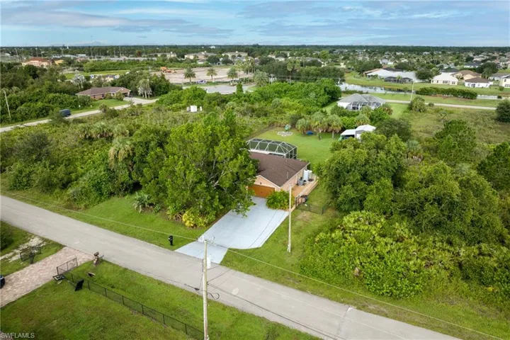 Aerial perspective of suburban area with a large body of water and a tree filled landscape