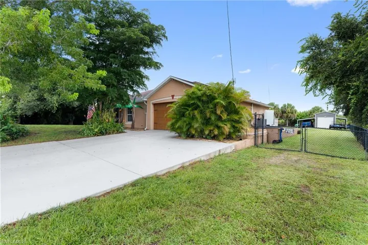 Obstructed view of property with concrete driveway, stucco siding, a garage, and a gate