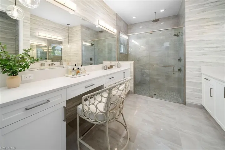 Full bath featuring vanity, a stall shower, and tile walls