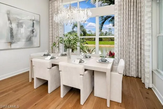 Dining area with wood finished floors, a chandelier, and a water view