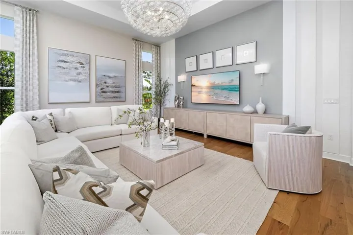 Living area with a chandelier, plenty of natural light, and wood finished floors