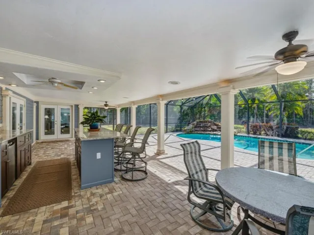 View of patio / terrace with ceiling fan, an outdoor bar and dining area, a sunroom, and an outdoor pool